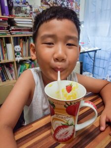 a child drinking mango shake with moringa - creative ways to feed moringa to your child
